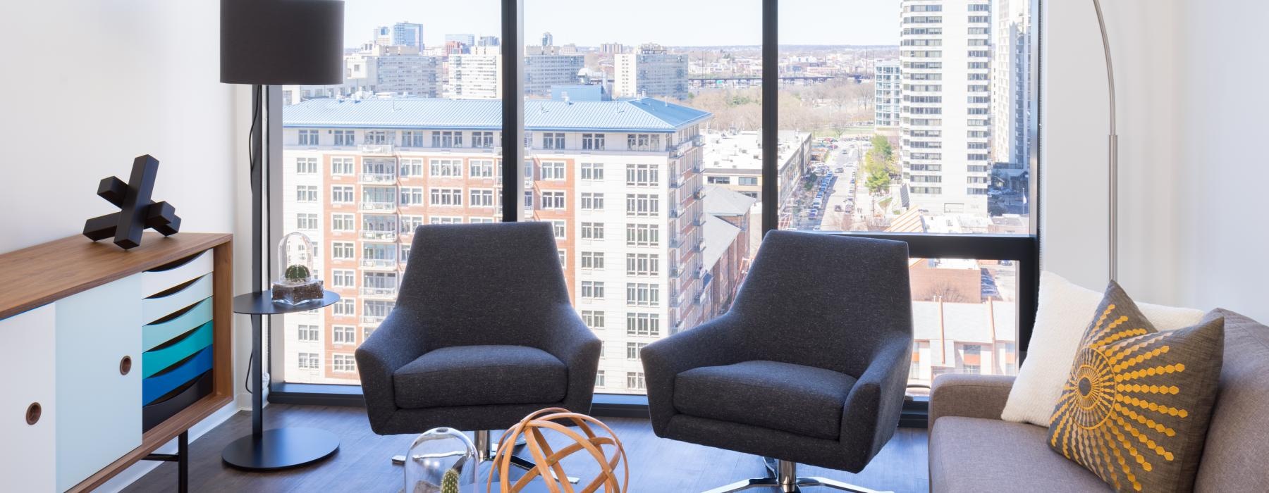 a room with a window and a couch with a table and chairs